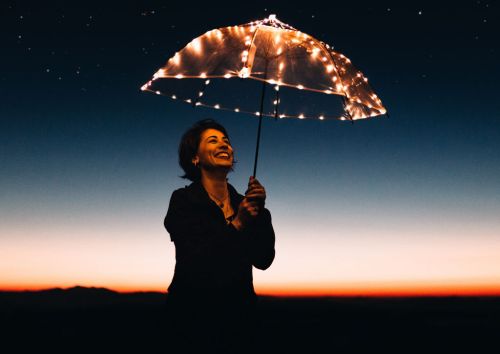 Kobieta z rozświetloną parasolką na tle nocnego nieba